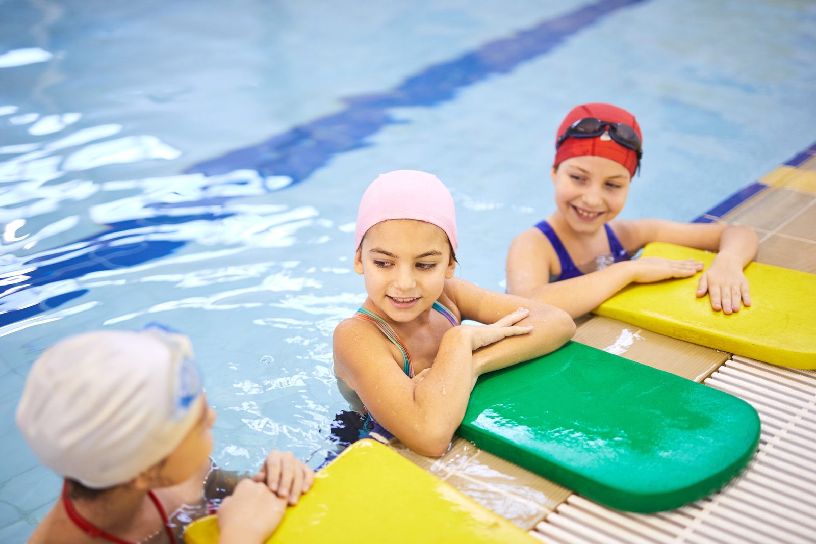 Kinder am beckenrand mit schwimmhilfen und reden zueinander